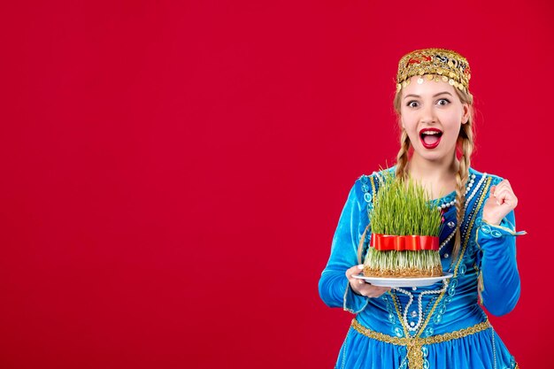 Portrait of azeri woman in traditional dress with green semeni on red background concept dancer spring ethnic