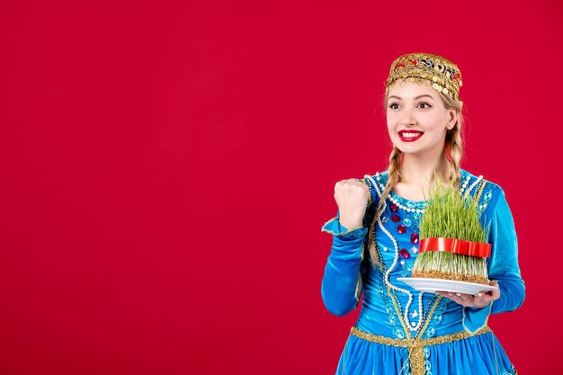 Portrait of azeri woman in traditional dress with green semeni on red background ethnic spring concept dancer