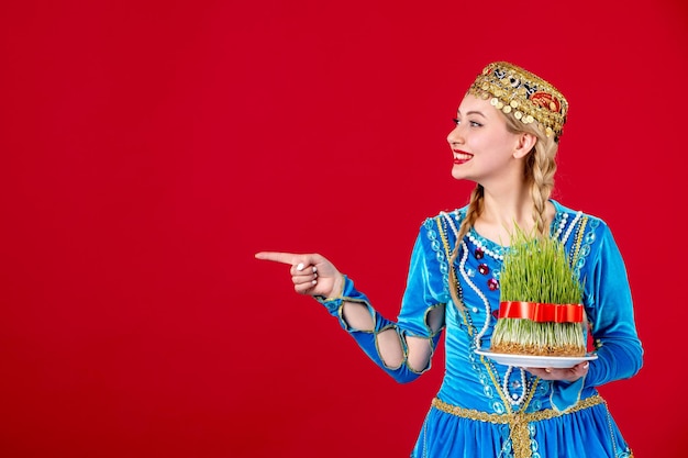 Portrait of azeri woman in traditional dress with green semeni on red background ethnic spring concept novruz photo
