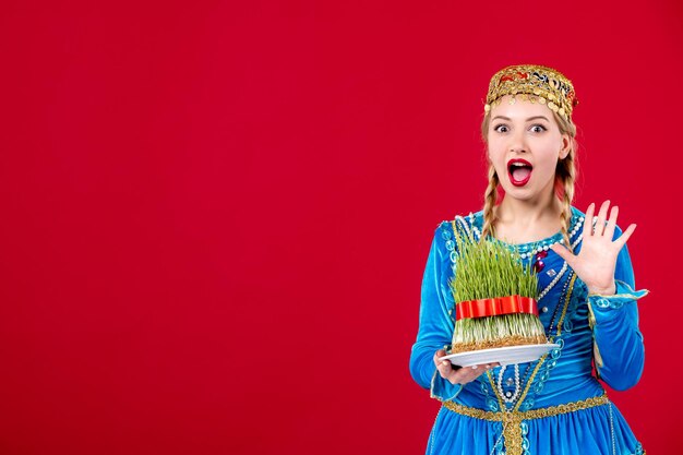 Portrait of azeri woman in traditional dress with green semeni on red background novruz ethnic concept spring colors