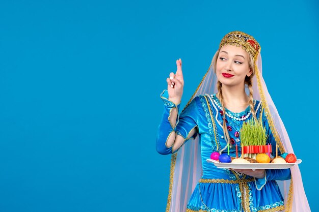 Portrait of azeri woman in traditional dress with novruz xonca blue background ethnic money dancer