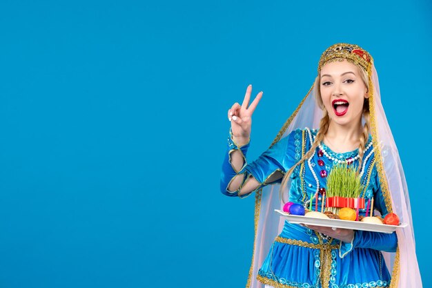 Portrait of azeri woman in traditional dress with novruz xonca blue background spring color ethnic money dancer