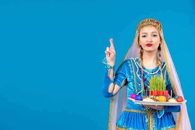 Portrait of azeri woman in traditional dress with novruz xonca blue background spring ethnic money dancers