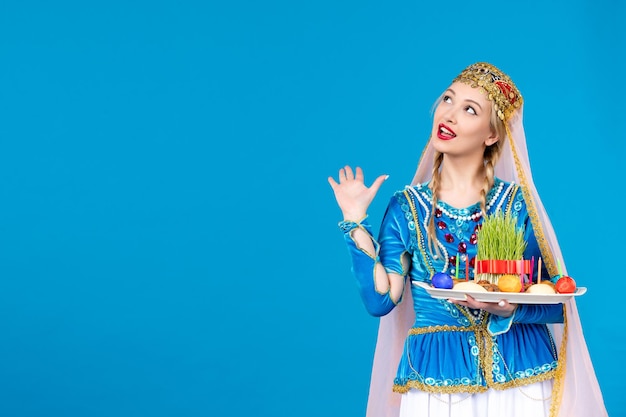 Free photo portrait of azeri woman in traditional dress with novruz xonca studio shot blue background concept dancer spring