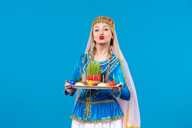 Portrait of azeri woman in traditional dress with novruz xonca studio shot blue background ethnic concept spring