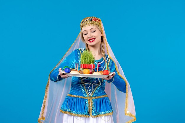 Portrait of azeri woman in traditional dress with novruz xonca studio shot blue background ethnic spring dancer colors