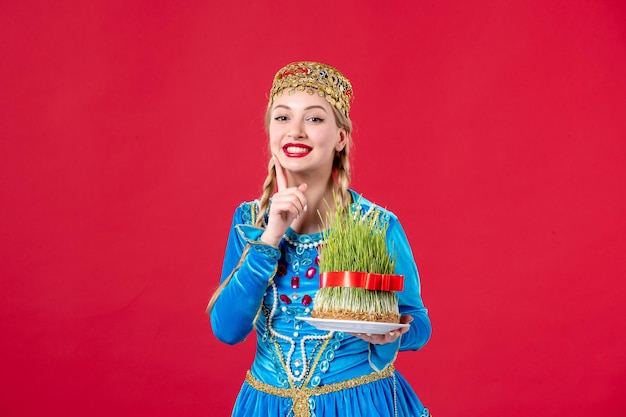 Portrait of azeri woman in traditional dress with semeni studio shot red background holiday concept spring novruz