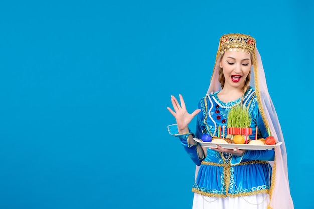 Portrait of azeri woman in traditional dress with xonca on blue background novruz concept ethnic dancer