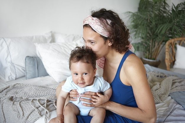 A portrait of a baby boy and mother sitting in bed