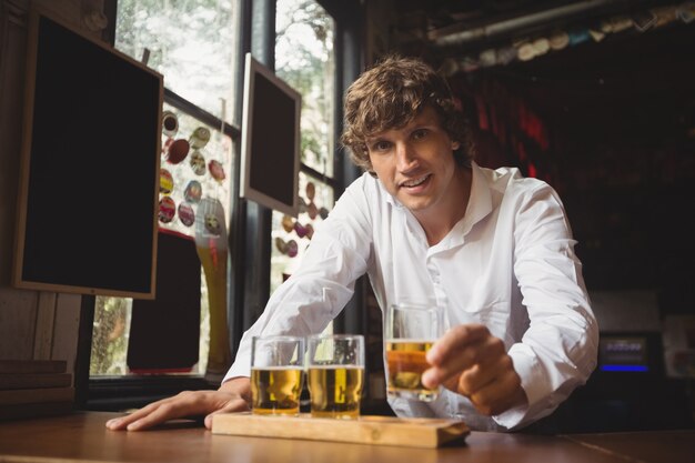 Portrait of bartender holding whisky shot glass at bar counter