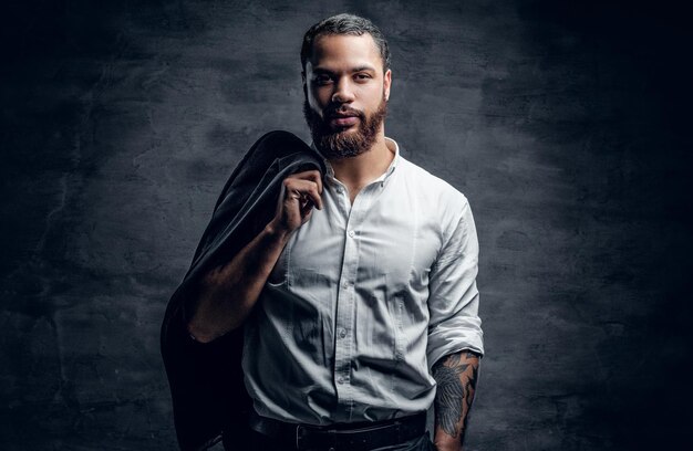 Portrait of bearded black man with tattooed arm wearing white shirt.