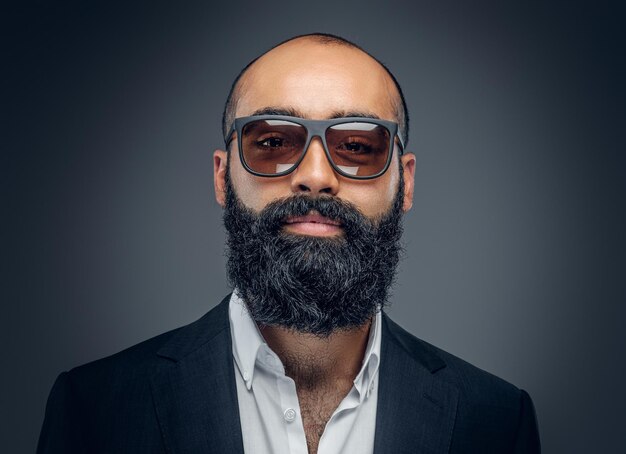 Portrait of bearded businessman dressed in a suit isolated on grey background.