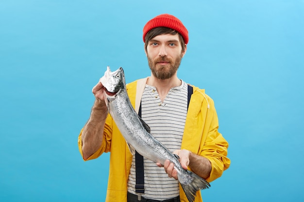 Free photo portrait of bearded fisherman standing with huge fish