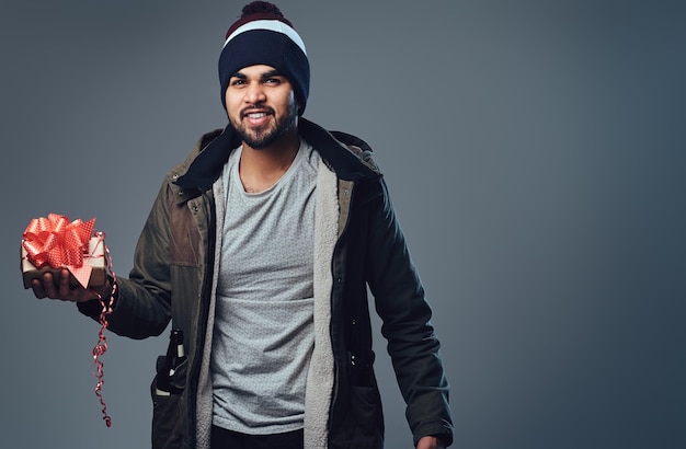 Free photo portrait of bearded indian male dressed in a winter jacket over grey background.