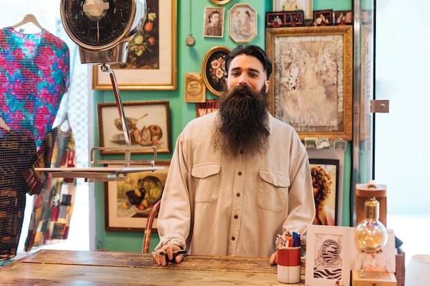 Free photo portrait of a bearded male owner standing in his shop