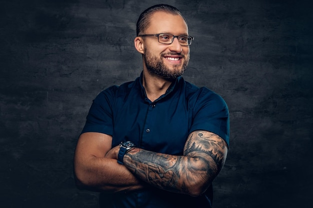 Portrait of bearded male in sunglasses with tattoo on his arm.