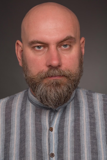 Foto gratuita ritratto di uomo barbuto in abito carcerario. uomo serio audace in camicia foderata in posa su grigio scuro.