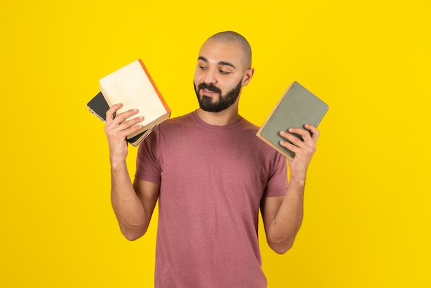 Portrait of a bearded man showing book cover  over yellow wall. 