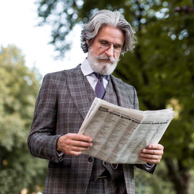 Портрет бородатого зрелого мужчины, читающего газету