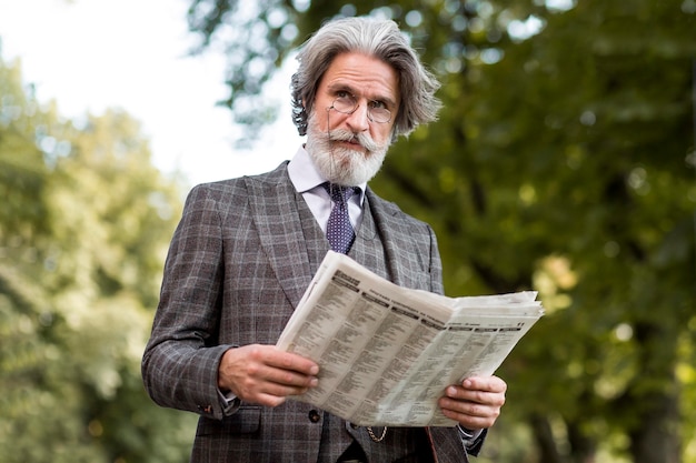 Portrait of bearded mature male reading newspaper