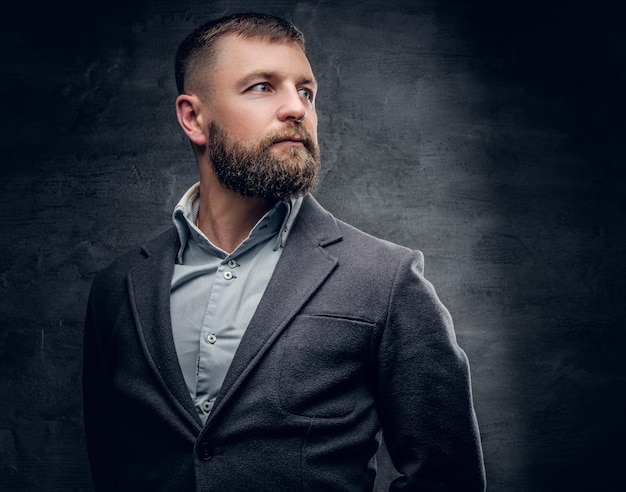 Portrait of bearded middle age male dressed in a woolen suit isolated on grey vignette background. Free Photo