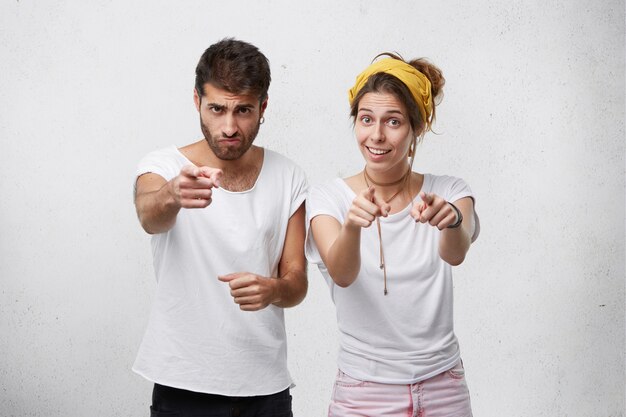 Portrait of bearded stylish man and pretty young woman wearing casual clothes pointing with fingers