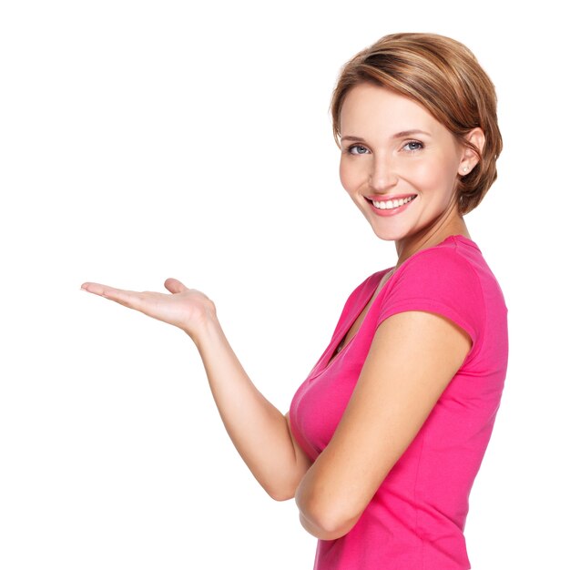 Portrait of a beautiful adult happy woman with presentation gesture over white wall