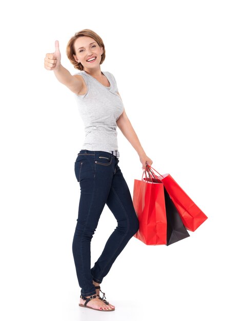 Portrait of a beautiful adult happy woman with thumbs up sign after shopping on white