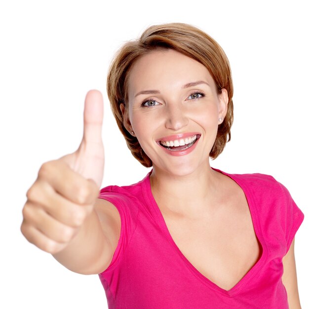 Портрет красивой взрослой счастливой женщины с большими пальцами руки вверх подписывает над белой стеной