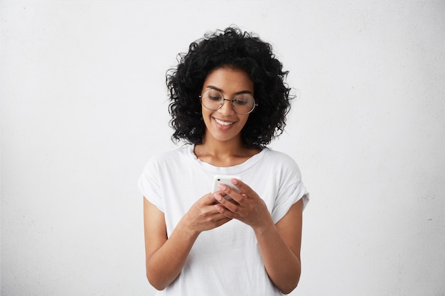 Portrait of beautiful African female student dressed casually holding cell phone