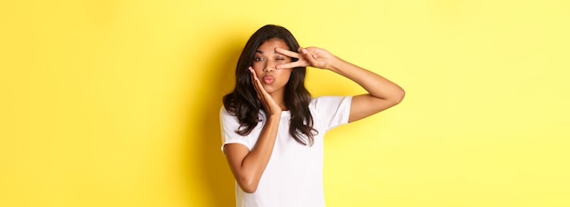 Portrait of beautiful africanamerican female model showing peace sign and pouting flirty standing si