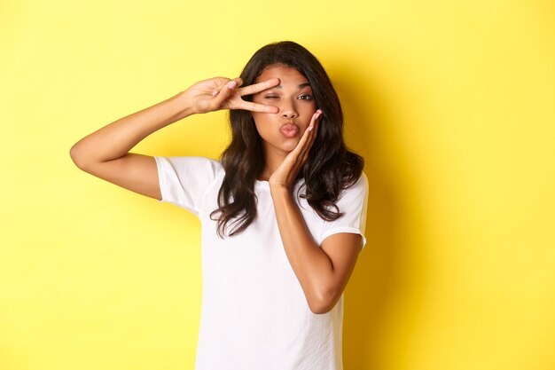 Portrait of beautiful africanamerican female model showing peace sign and pouting flirty standing