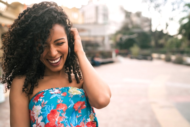 通りで笑っている美しいアフロアメリカンラテン自信のある女性の肖像画。屋外。