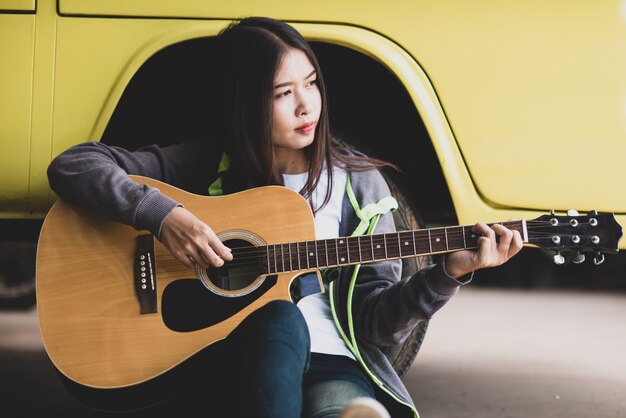 アコースティックギターを保持している肖像画美しいアジアの女性