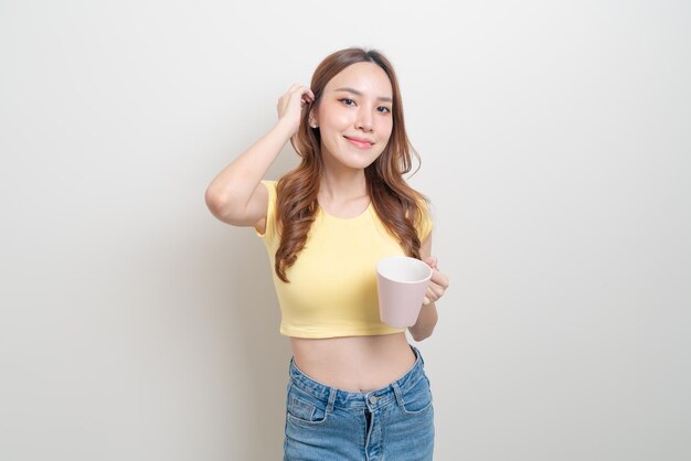 Портрет красивой азиатской женщины, держащей чашку кофе или кружку на белом фоне