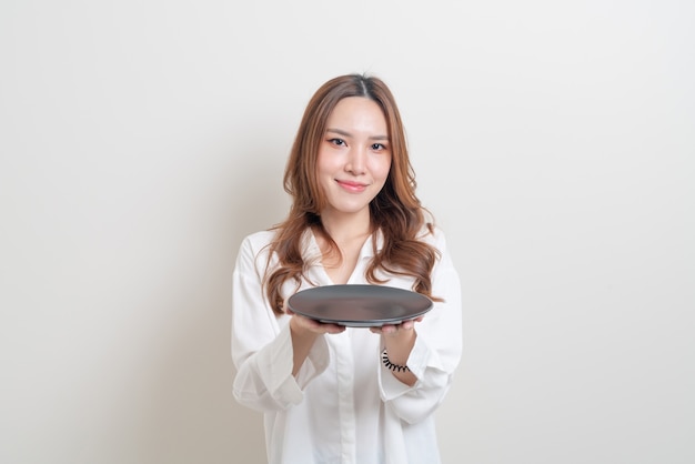 Портрет красивой азиатской женщины, держащей пустую тарелку на белом фоне