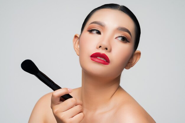 Portrait of Beautiful Asian woman holding makeup blusher brush