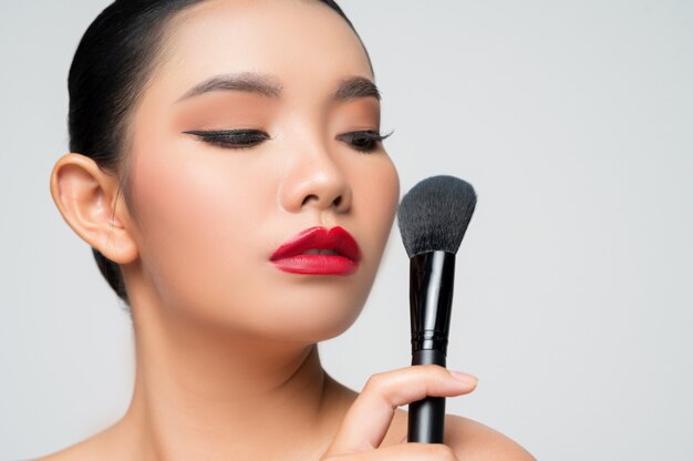 Portrait of Beautiful Asian woman holding makeup blusher brush