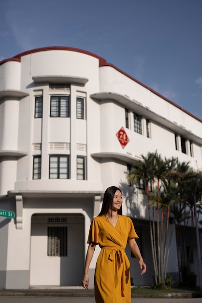 Free photo portrait of beautiful asian woman posing in the city while wearing yellow dress