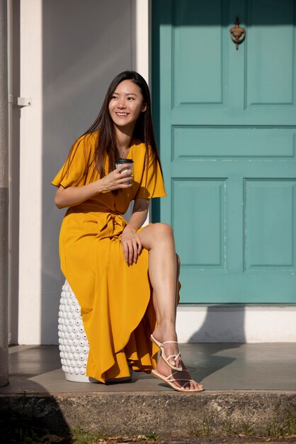 Portrait of beautiful asian woman posing outdoors in the city while having coffee