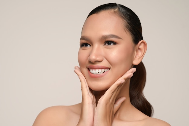 Portrait of beautiful asian woman touches cheek and smiles