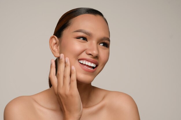 Portrait of beautiful asian woman touches cheek and smiles