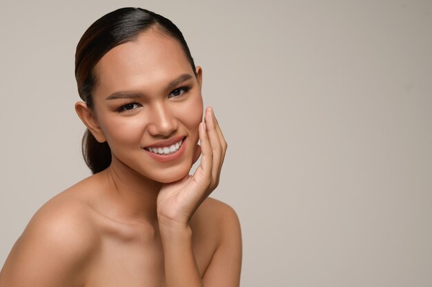 Portrait of beautiful asian woman touches cheek and smiles