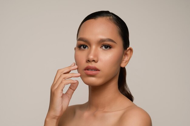 Portrait of beautiful asian woman touches cheek and smiles