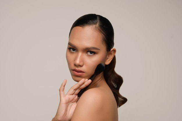 Portrait of beautiful asian woman touches cheek and smiles