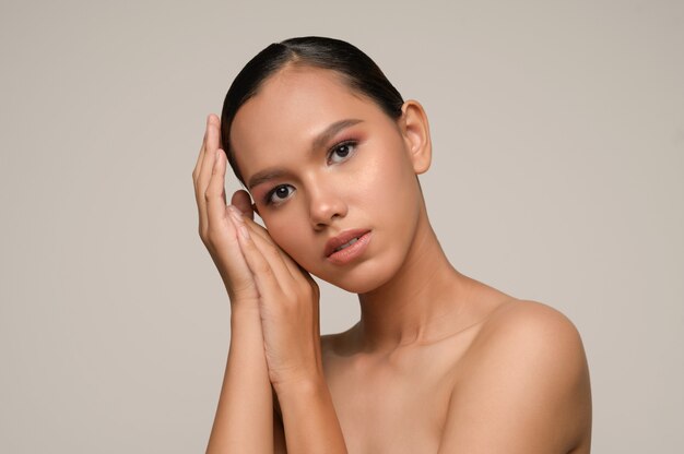 Portrait of beautiful asian woman touches cheek and smiles