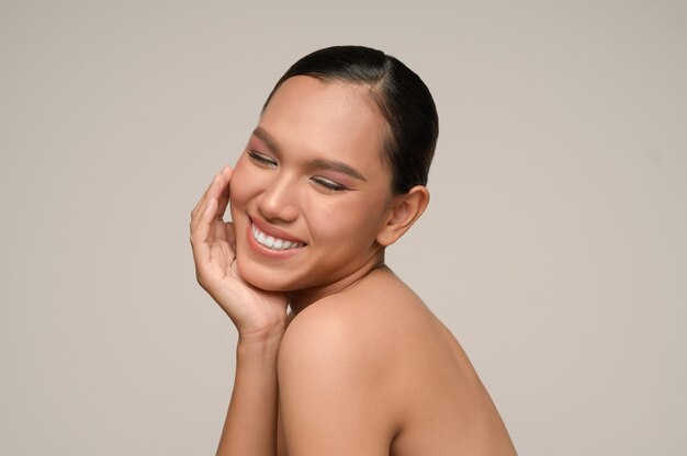 Portrait of beautiful asian woman touches cheek and smiles