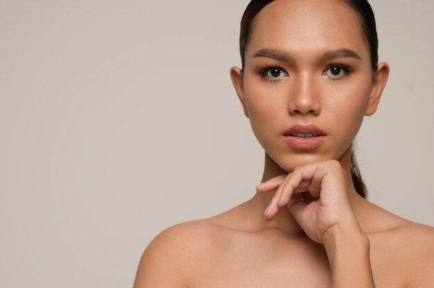 Portrait of beautiful asian woman touches chin and looks at front