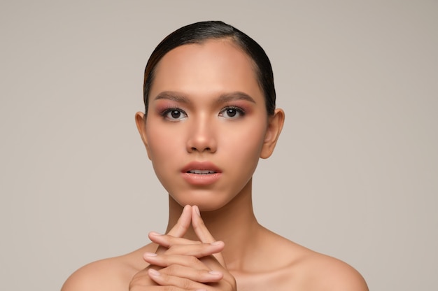 Portrait of beautiful asian woman touches chin with beautiful natural clean skin