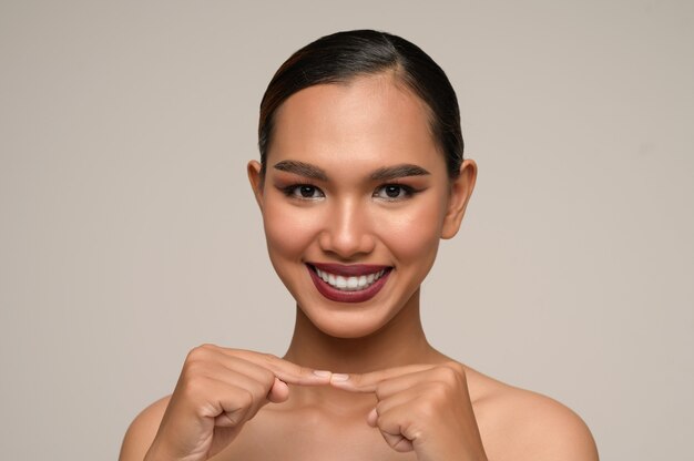 Портрет красивой азиатской женщины касается пальца и пальца с большими улыбками